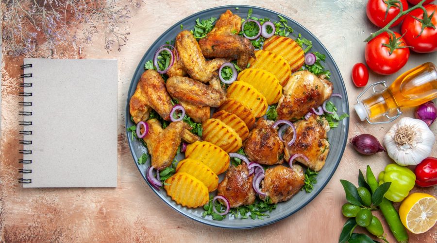 top-close-up-view-chicken-chicken-wings-potatoes-onion-herbs-vegetables-white-notebook